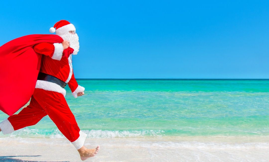 Santa running with a bag of gifts on the beach